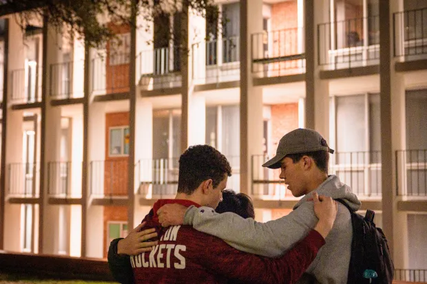 three male students praying for each other on campus