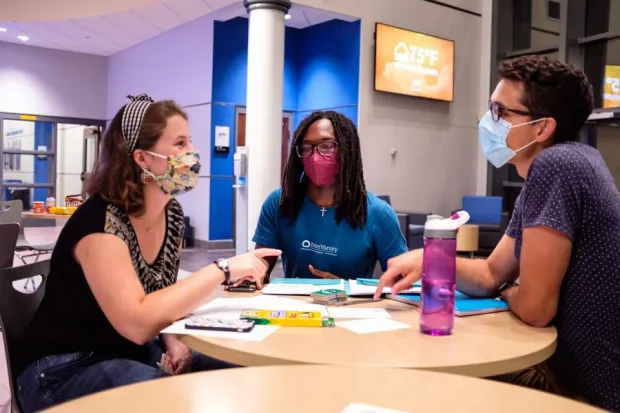 Student and campus ministers meeting at tables in lounge