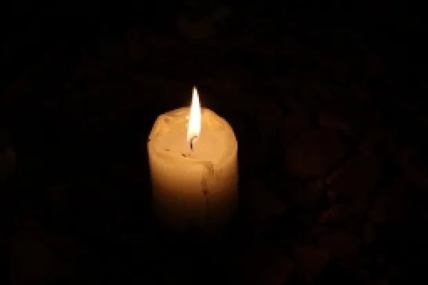 a small candle burning in darkness
