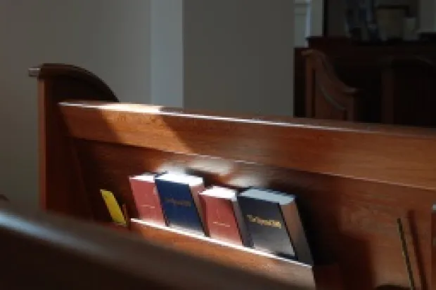 Empty pew with Bibles and hymnbooks in rack
