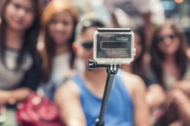 a person holding a selfie stick in front of their friends