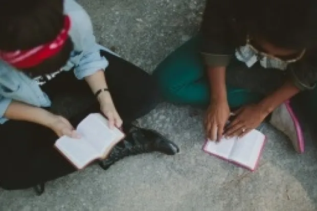 Two women seated on floor studying Scripture