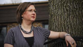 Woman sitting on bench outside looking thoughtful