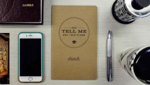 Office desk with phone, pen, Bible, coffee tumbler, and notebook with the words "Just tell me what I need to know about church."