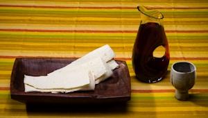 Communion elements on table: strips of flatbread on a wooden plate, a pitcher of juice, and a plain ceramic cup