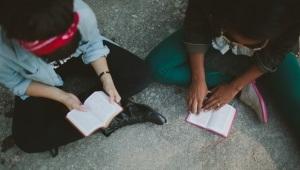 Two women seated on floor studying Scripture