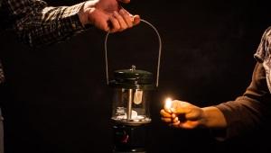 a person lighting a lantern in the dark.