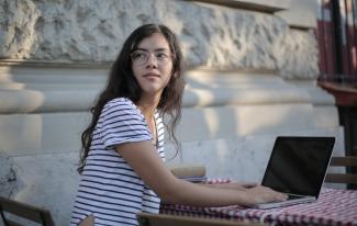 Young woman sitting outside working on computer
