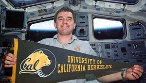 Rex Walheim holding a University of California, Berkeley Banner in space shuttle cockpit
