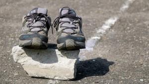 Pair of running shoes sitting on top of rock on the pavement