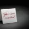 folded white paper that stands up and says "you are invited" in red letters