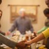 people of different ethnicities holding hands and praying across a dinner table
