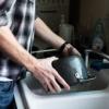 Man washing dishes in kitchen sink
