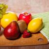 Variety of fruit on cutting board beside kitchen knife and towel