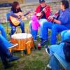 Native family gathering of all ages talking and playing music with guitars and drum