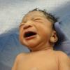 Closeup of newborn crying held by doctor