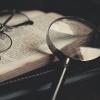 A magnifying glass and eyeglasses resting on a book