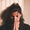 a young woman praying with her hands folded in front of her face